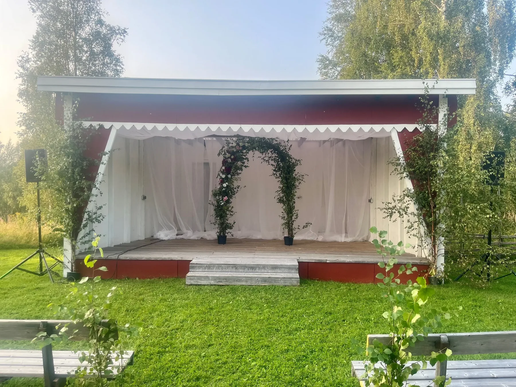 Utomhusscen klädd i vitt med blomsterbåge inför bröllop